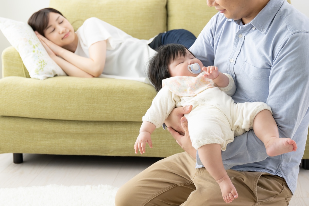 休む母と赤ちゃんを抱っこする父