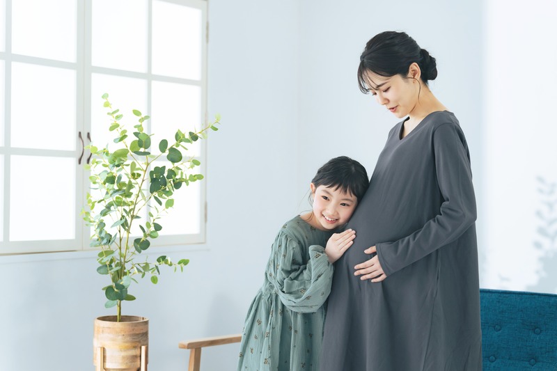 お母さんのおなかに耳をあてる女の子
