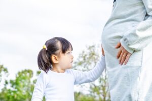ママのおなかに手を当てる子供